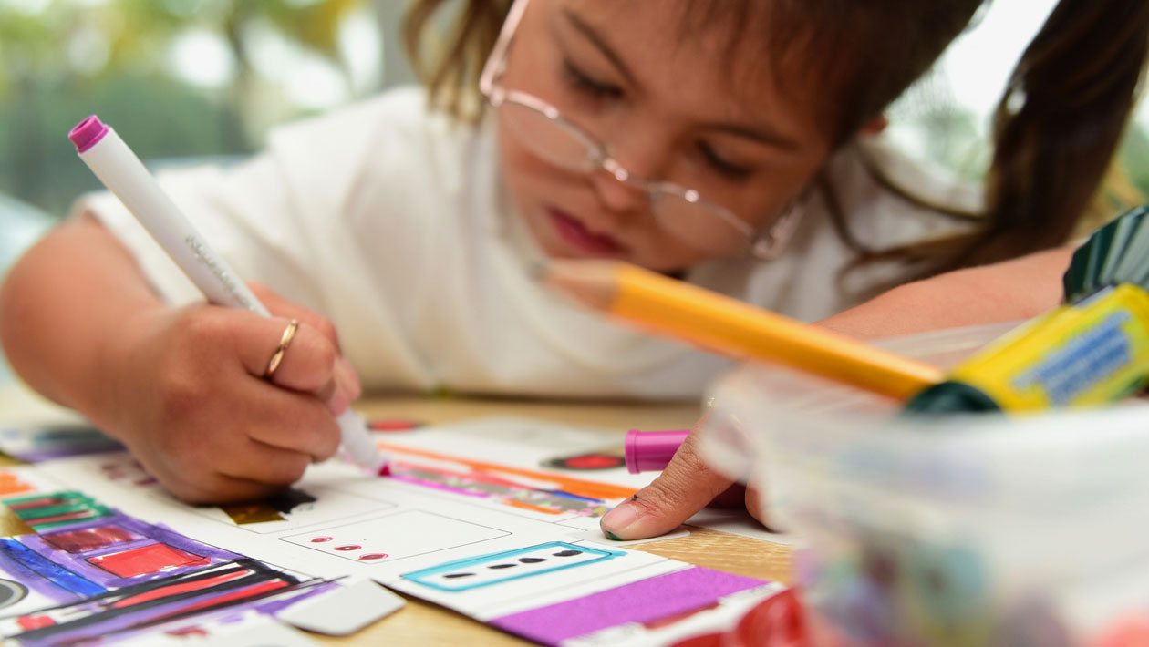 Girl with glasses coloring with a pink marker